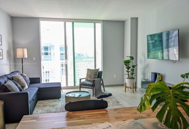 living room with hardwood / wood-style flooring, a wall of windows, plenty of natural light, and a textured ceiling