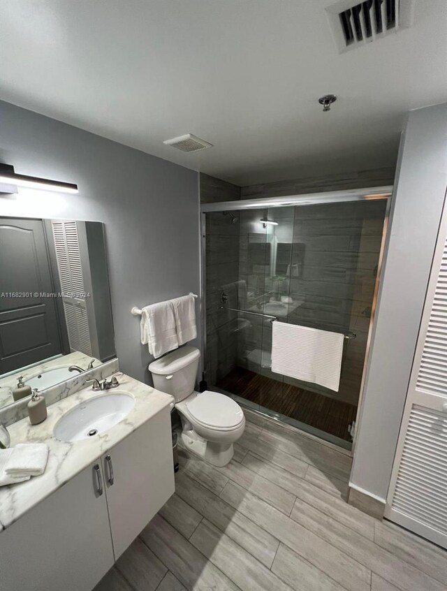 bathroom with walk in shower, vanity, and toilet