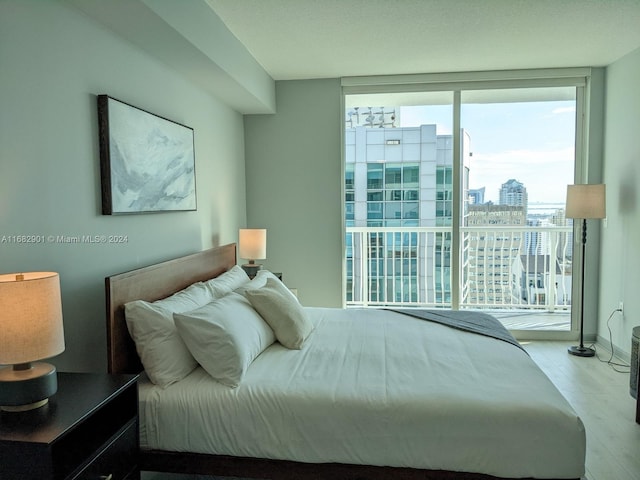 bedroom with expansive windows, light hardwood / wood-style flooring, and multiple windows