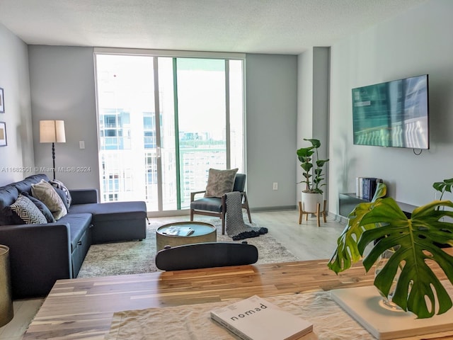 living room featuring hardwood / wood-style flooring, a wall of windows, and a textured ceiling