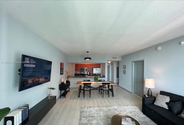 living room with light wood-type flooring and a textured ceiling