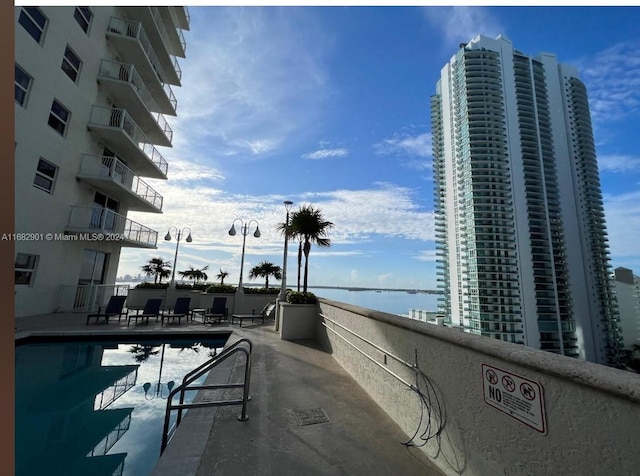 view of swimming pool featuring a water view and a patio area