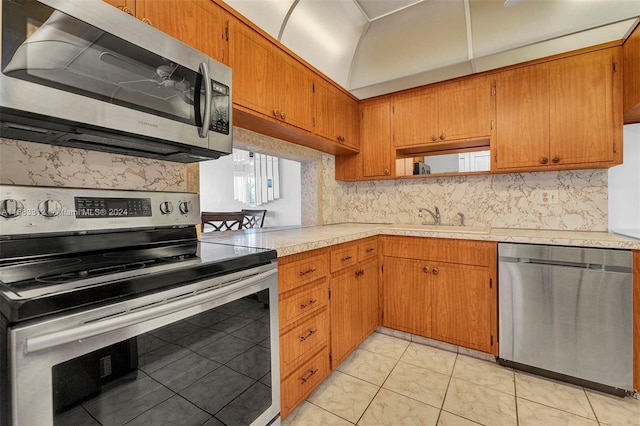 kitchen featuring sink, backsplash, appliances with stainless steel finishes, and light tile patterned floors