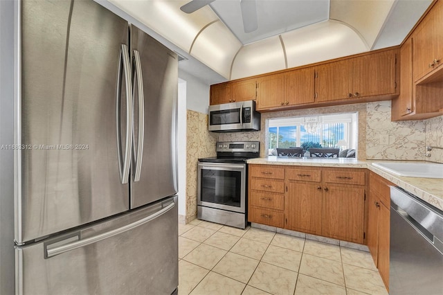 kitchen with light tile patterned flooring, appliances with stainless steel finishes, sink, and decorative backsplash