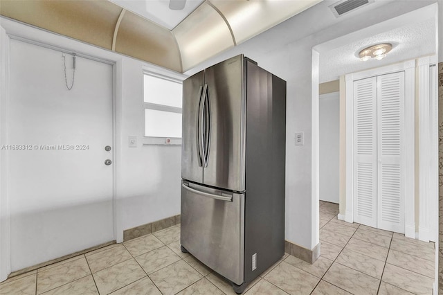 kitchen with stainless steel fridge, a textured ceiling, and light tile patterned floors