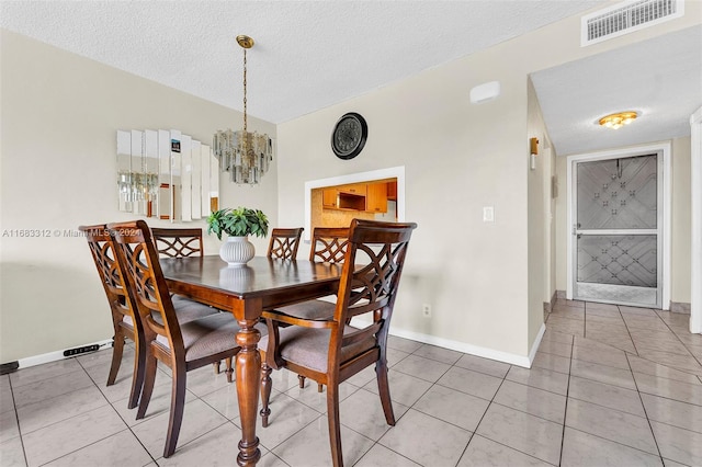 dining room featuring light tile patterned floors, a textured ceiling, and an inviting chandelier