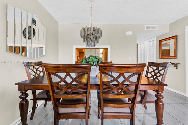 dining area featuring a notable chandelier, a textured ceiling, and tile patterned floors