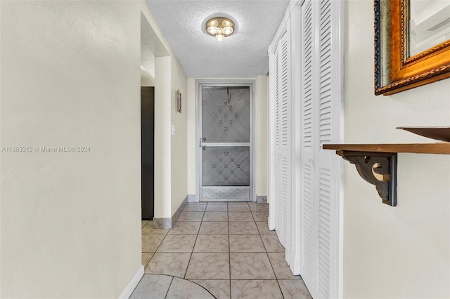 corridor with a textured ceiling and light tile patterned flooring