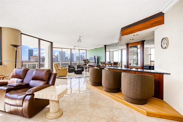 living room with a healthy amount of sunlight, a textured ceiling, light tile patterned floors, and a wall of windows