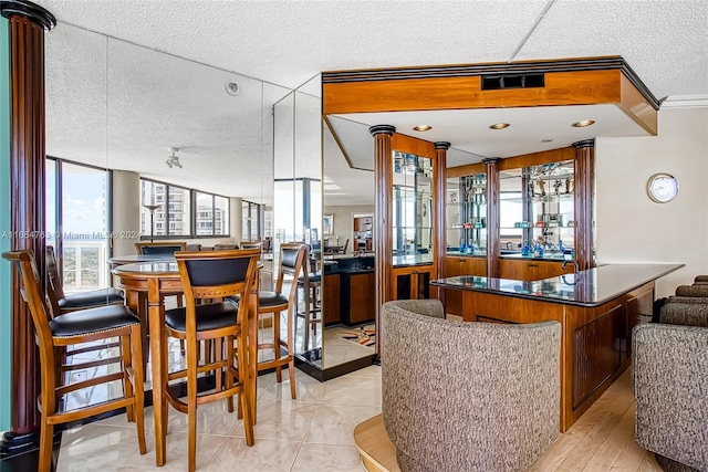 bar featuring light hardwood / wood-style floors, ornamental molding, and a textured ceiling