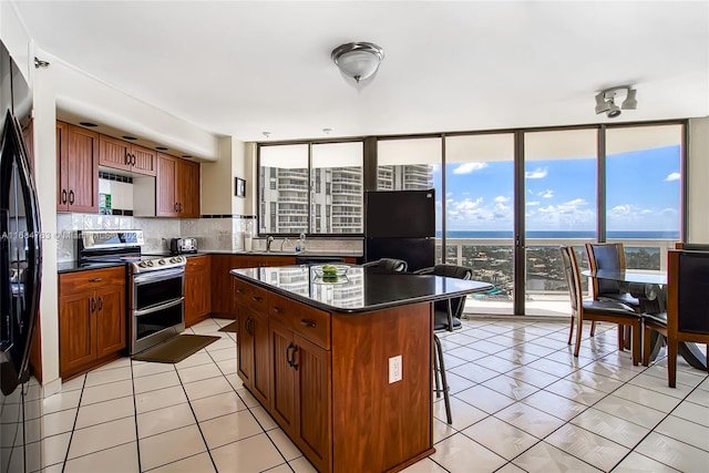 kitchen with tasteful backsplash, black refrigerator, plenty of natural light, stainless steel range with electric stovetop, and a center island