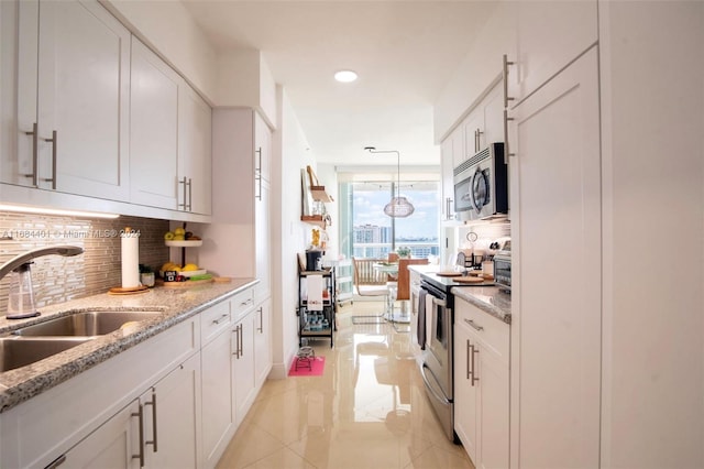 kitchen with hanging light fixtures, sink, white cabinets, appliances with stainless steel finishes, and tasteful backsplash