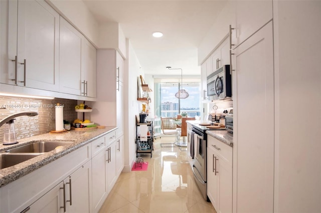 16400 Collins Ave Unit 1444, Sunny Isles Beach, FL 33160 - kitchen featuring stainless steel appliances, decorative backsplash, white cabinetry, light stone countertops, and recessed lighting