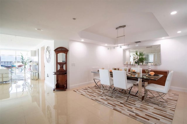 tiled dining space with a raised ceiling