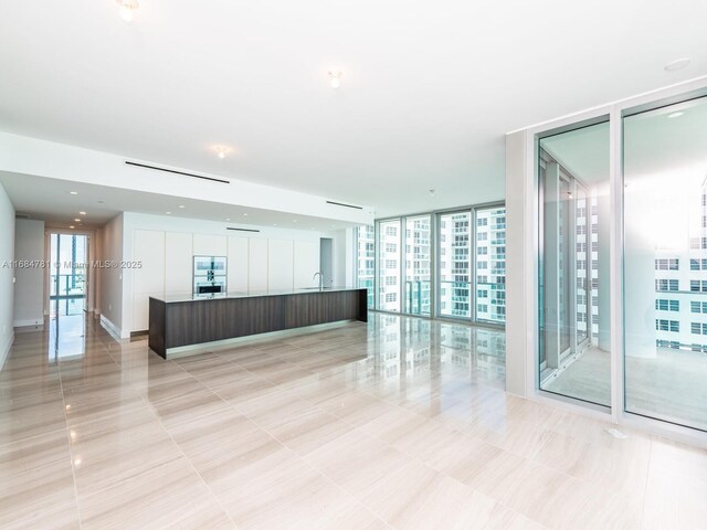 kitchen featuring a large island with sink, sink, dark brown cabinetry, expansive windows, and a water view