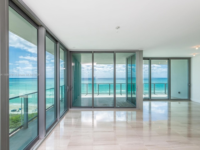 empty room with a water view, light tile patterned flooring, and floor to ceiling windows