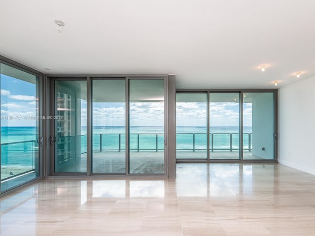 spare room with a water view, light tile patterned floors, and floor to ceiling windows