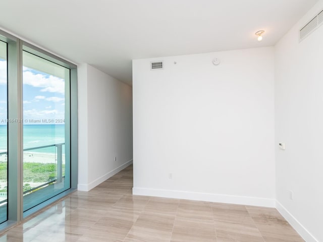 unfurnished room featuring a wall of windows and a water view