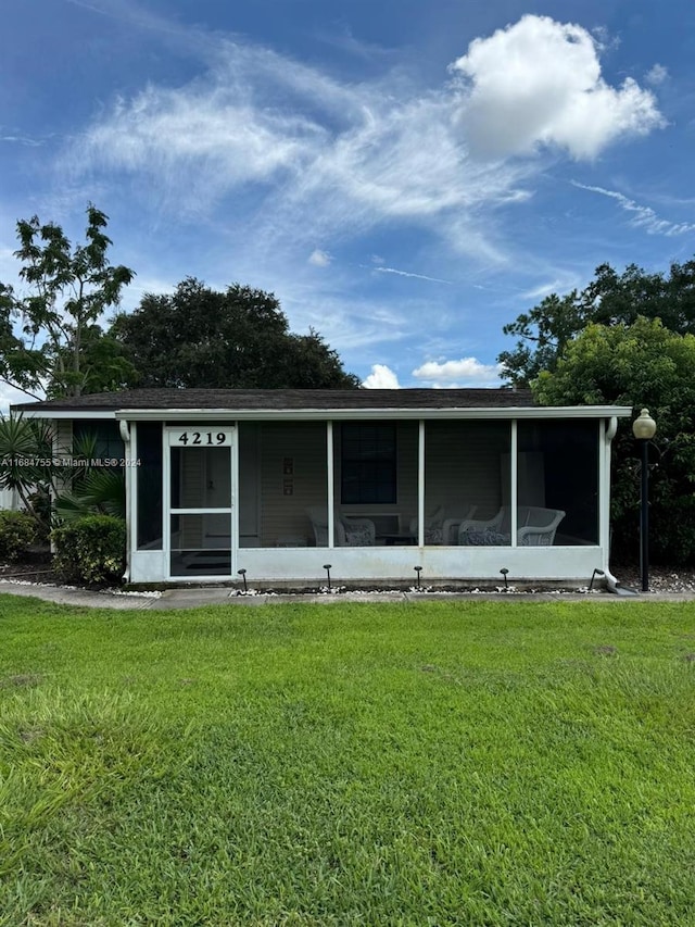 view of front of house with a sunroom and a front lawn