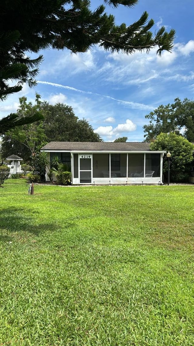 back of property featuring a sunroom and a lawn