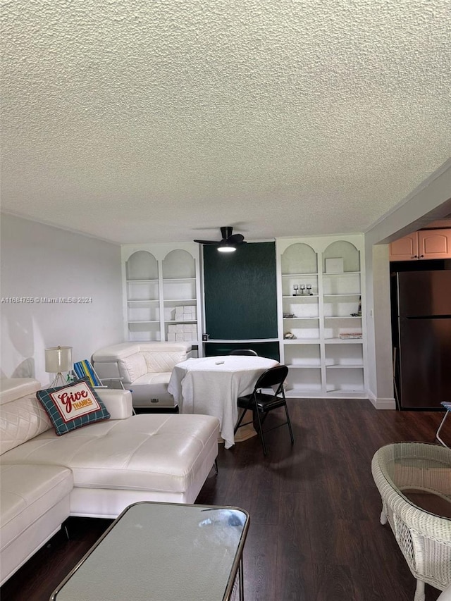 living room featuring a textured ceiling, wood-type flooring, and built in shelves