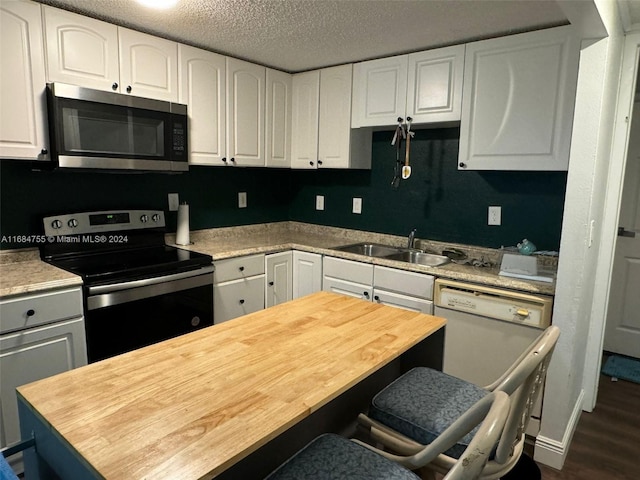 kitchen with sink, appliances with stainless steel finishes, white cabinets, and dark hardwood / wood-style flooring