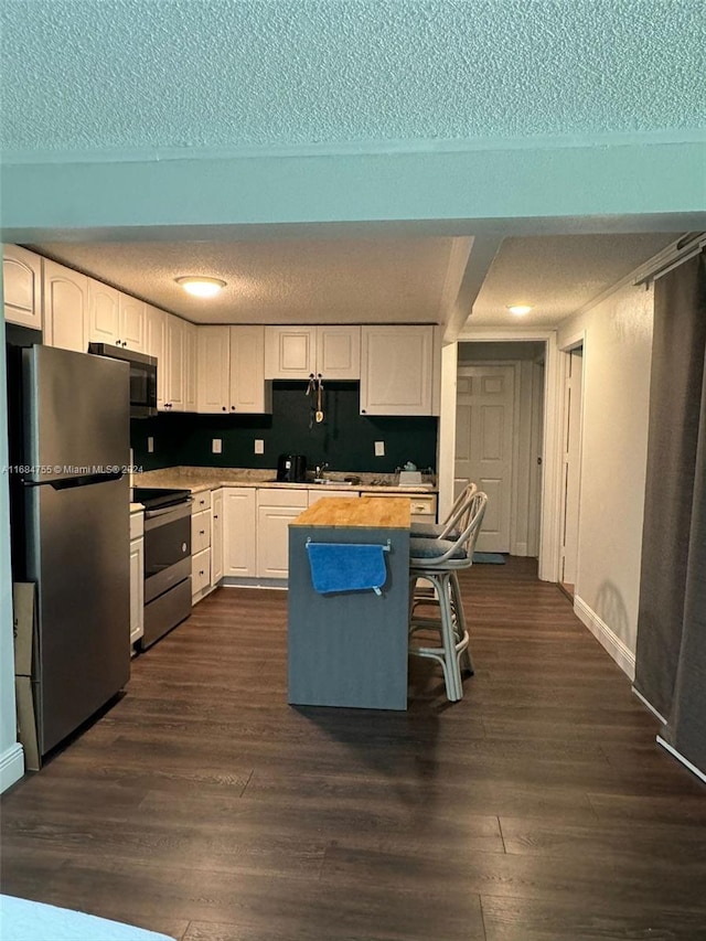 kitchen with dark hardwood / wood-style floors, white cabinetry, stainless steel appliances, and a textured ceiling