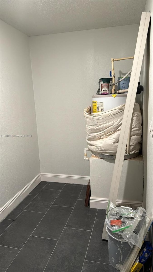 washroom with a textured ceiling and dark tile patterned flooring