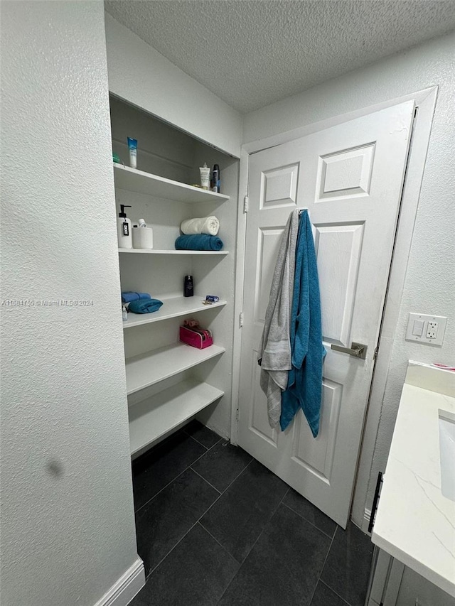 mudroom featuring a textured ceiling and dark tile patterned floors