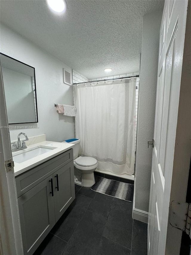 bathroom with vanity, toilet, a textured ceiling, and tile patterned flooring