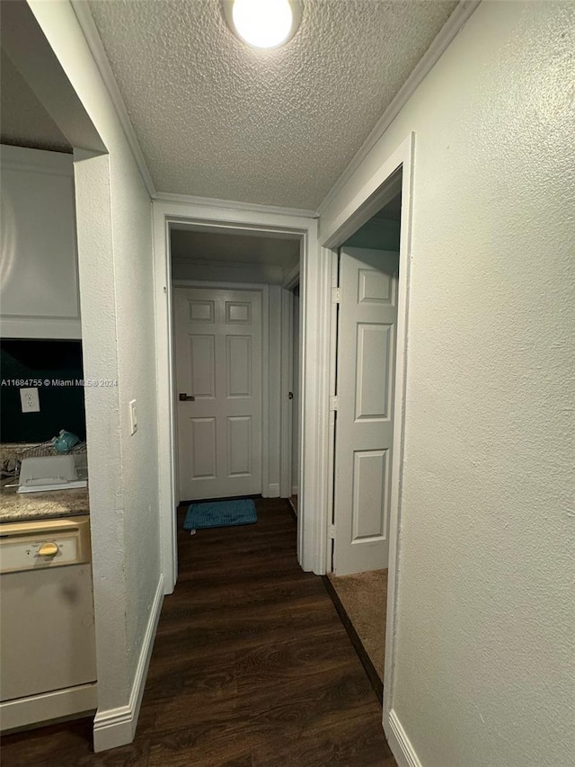 corridor with ornamental molding, a textured ceiling, and dark hardwood / wood-style flooring