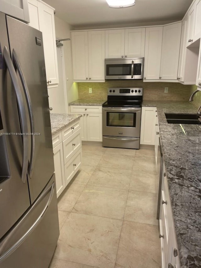 kitchen featuring white cabinetry, stainless steel appliances, stone counters, and sink