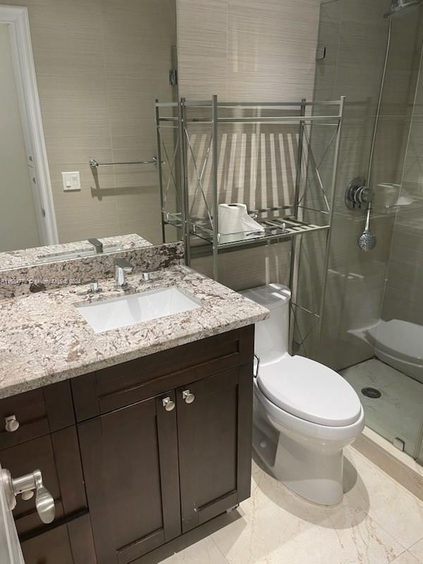 bathroom featuring vanity, toilet, and a shower with shower door