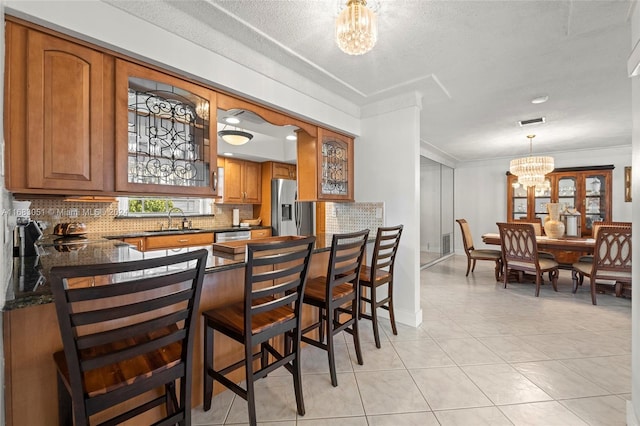 kitchen with tasteful backsplash, appliances with stainless steel finishes, sink, a kitchen bar, and an inviting chandelier