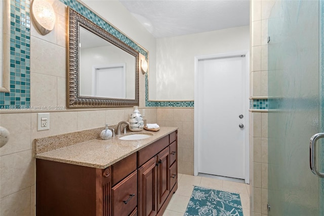 bathroom with vanity, tile patterned floors, tile walls, and an enclosed shower