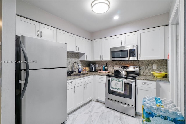 kitchen featuring light stone counters, stainless steel appliances, decorative backsplash, and white cabinets