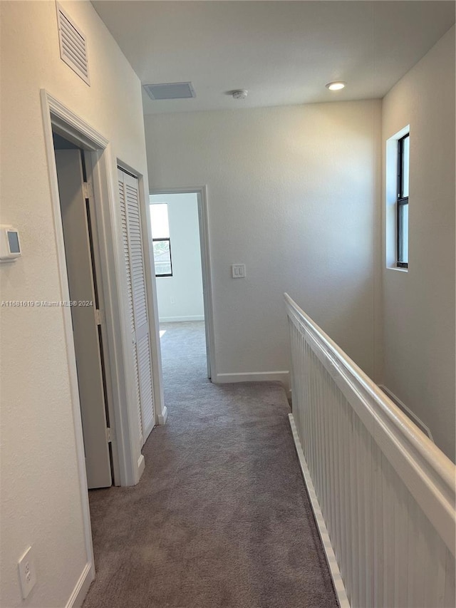 hallway with carpet, visible vents, and baseboards
