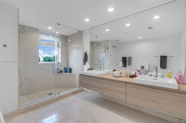 bathroom with a shower with door, vanity, and tile patterned floors