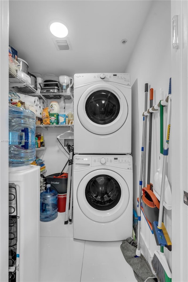 clothes washing area featuring stacked washer and dryer and tile patterned floors