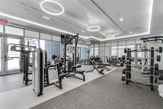 exercise room with carpet floors and a tray ceiling