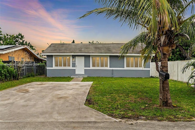 view of front of home with stucco siding, a yard, and fence