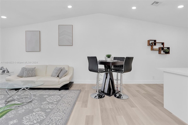 living room with light wood-type flooring and vaulted ceiling