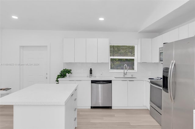 kitchen with a kitchen island, white cabinetry, sink, light hardwood / wood-style floors, and stainless steel appliances