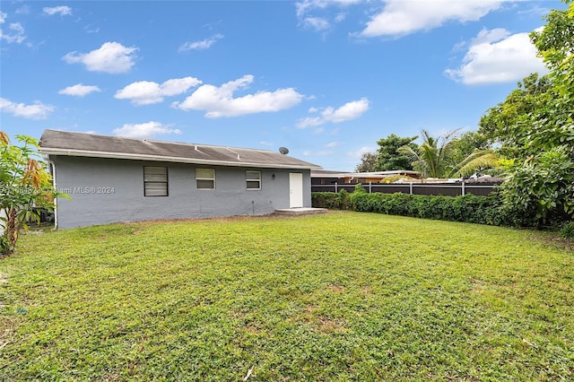 rear view of property featuring a fenced backyard, stucco siding, and a yard