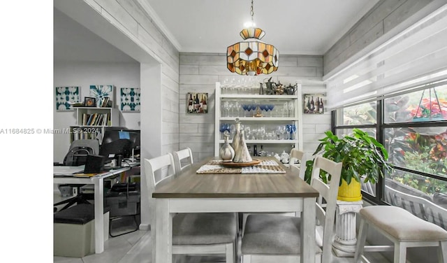 dining space with crown molding and wood walls