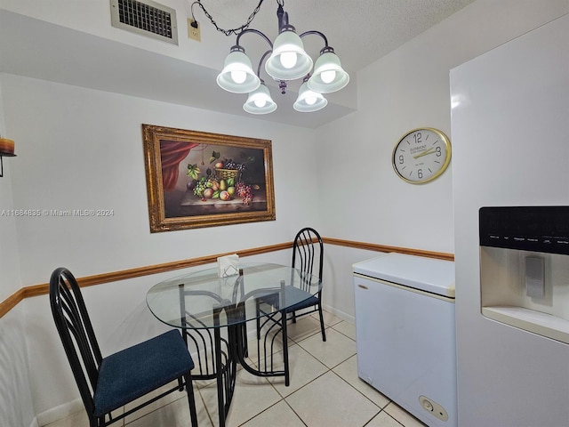 tiled dining space with a notable chandelier and a textured ceiling