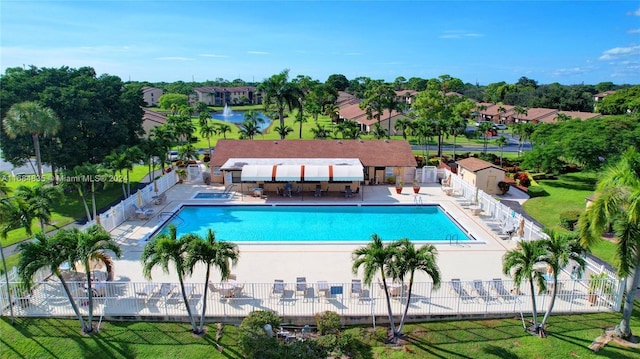 view of pool with a water view, a patio area, and a lawn