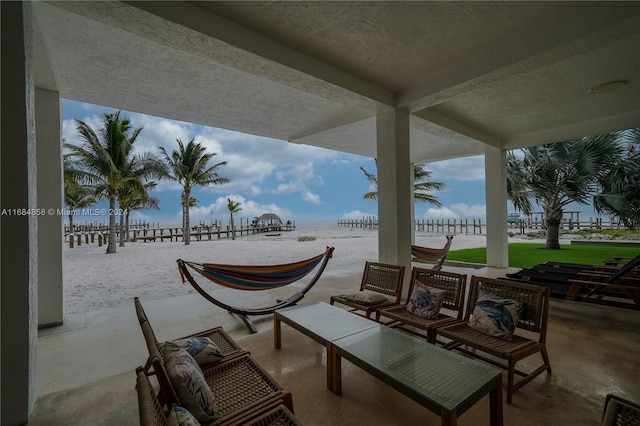 view of patio with a water view, a view of the beach, and an outdoor living space