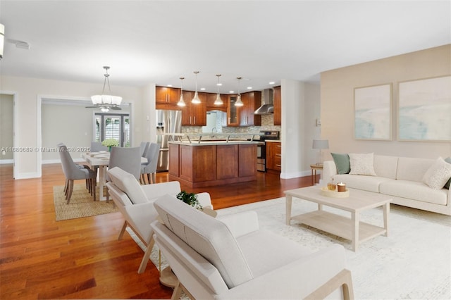 living area featuring an inviting chandelier, light wood-style flooring, and baseboards