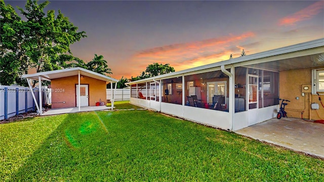 yard at dusk featuring a patio area and a sunroom